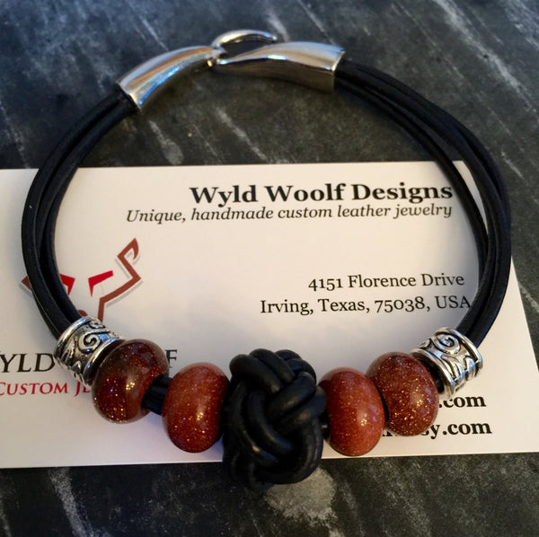 Leather cord bracelet, black leather, beaded goldstone beads and black eternity knot center piece,